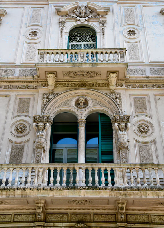 Due balconi della facciata del palazzo storico intitolato a Giuseppe Giordano con persiane verdi