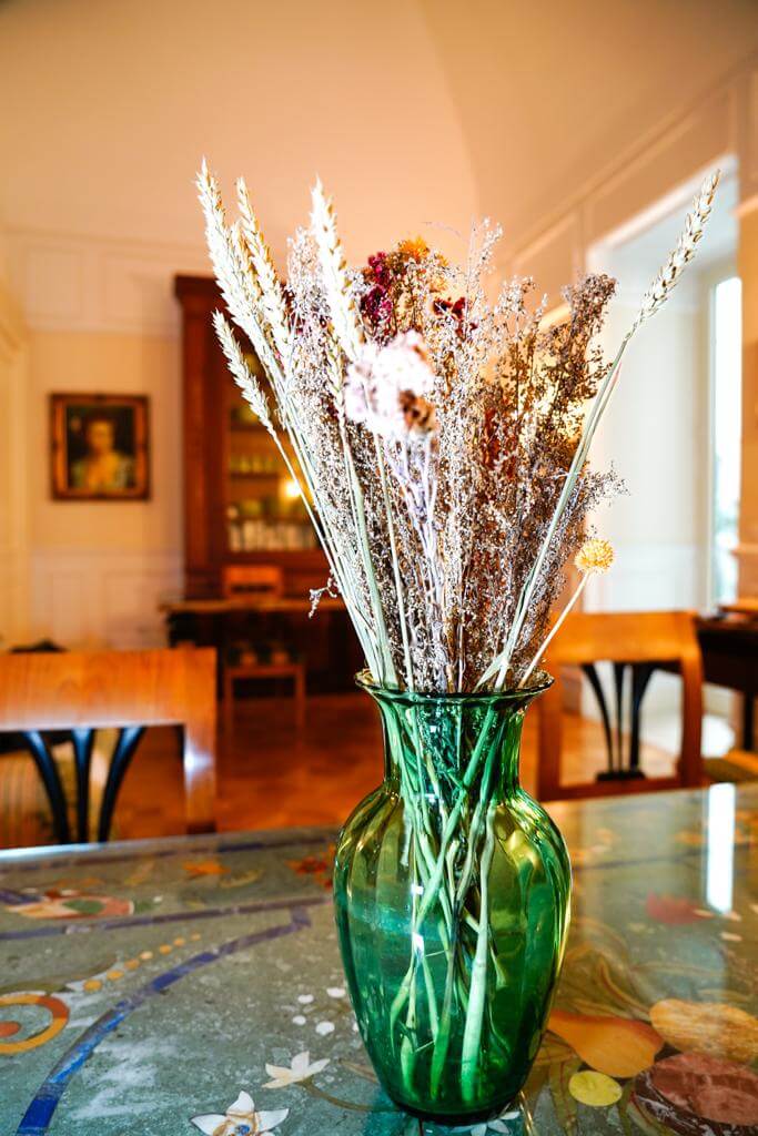 Vaso verde in vetro con fiori secchi decorativi, sfondo arredi in stile classico